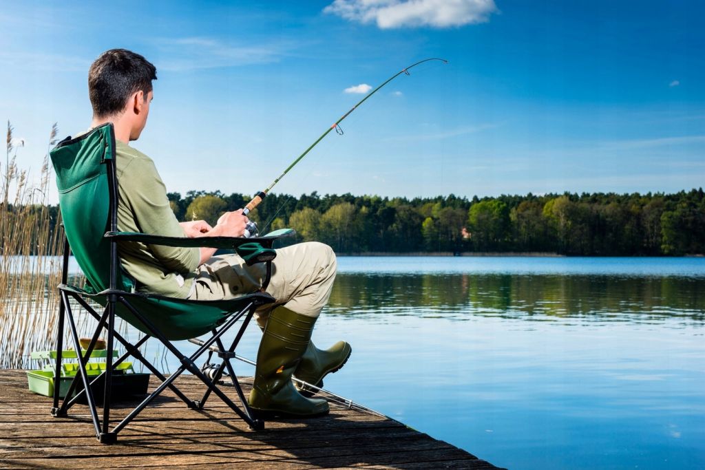 Мужчина сидит в кресле на рыбалке фото